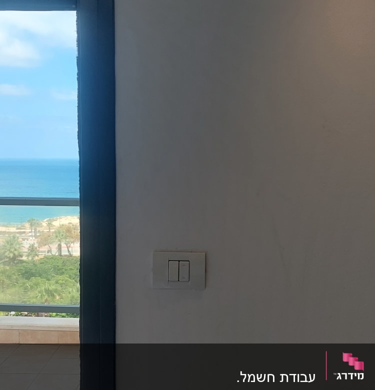 מתג חשמל על קיר לבן ליד חלון